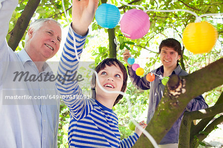 Three generation family putting fairy lights in tree