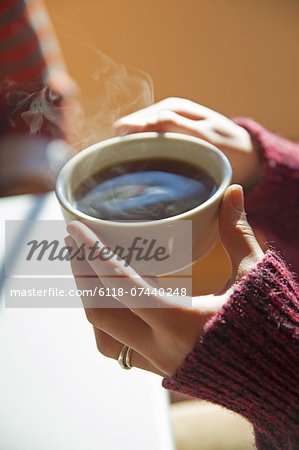 A woman holding a cup of hot coffee in her hands.