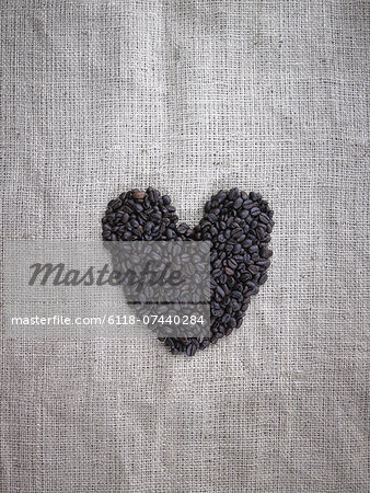 Organic roasted coffee beans in a heart shape on a burlap sack.