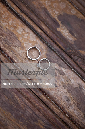 Platinum wedding rings . Two rings on a worn scrubbed stained wooden surface.