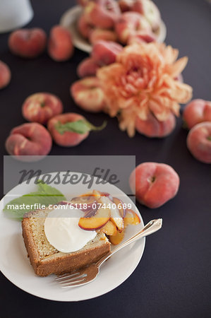 Fresh fruit and flowers. A slice of organic peach cake with a serving of creme fraiche and doughnut peaches.