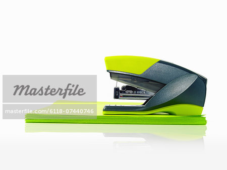 A blue and green plastic stapler, and green post it notes.