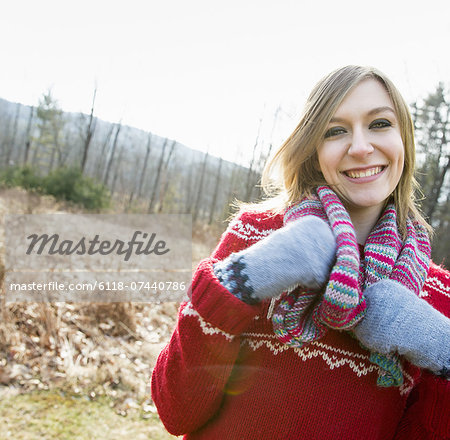 A woman wearing a knitted scarf and woollen mittens outdoors on a winter day.