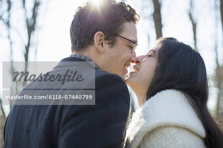 Two people, a couple, a man and woman in the woods on a winter day. Kissing.
