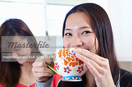 Two young women in kitchen having coffee break