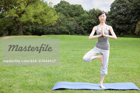 Young woman in park practicing yoga tree pose