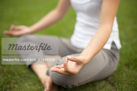 Cropped image of young woman in park practicing lotus position