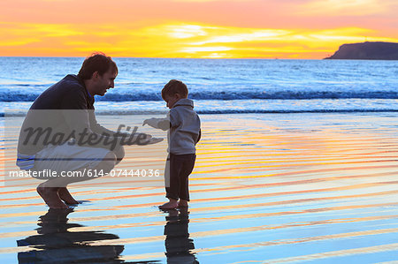 Father and toddler son playing on beach, San Diego, California, USA