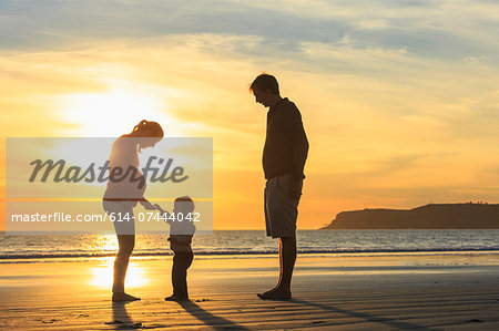 Family and toddler son playing on beach at sunset, San Diego, California, USA