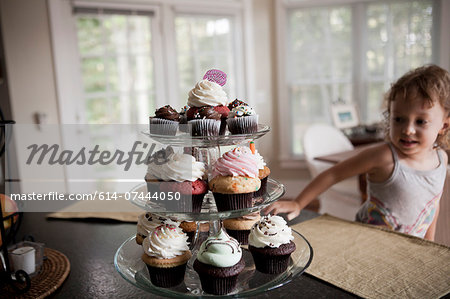 Female toddler looking at cake stand full of cupcakes