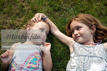 Portrait of two young sisters lying on grass