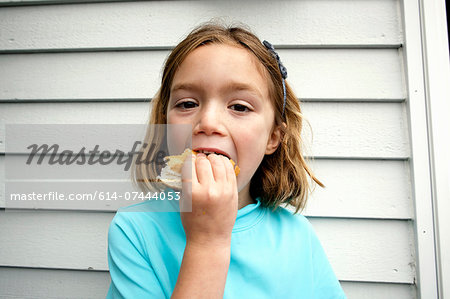 Young girl greedily eating sandwich