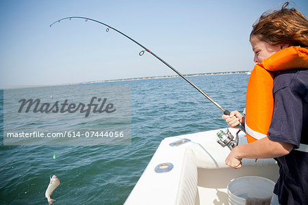 Boy catching fish from boat,  Falmouth, Massachusetts, USA