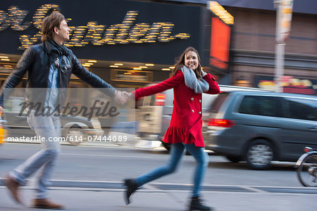 Young couple running along street, New York City, USA