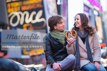 Young couple sharing pretzel, New York City, USA