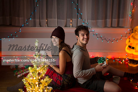 Young couple exchanging gifts in sitting room at christmas