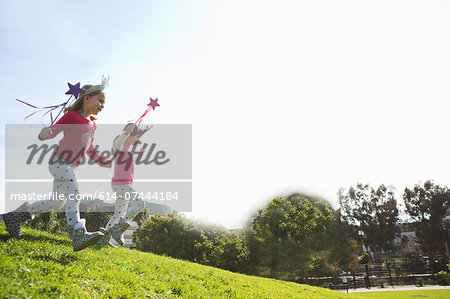 Two young sisters dressed up as fairies running down hill Two young sisters dressed up as fairies running down hill