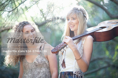 Two teenage girls with acoustic guitar in woodland