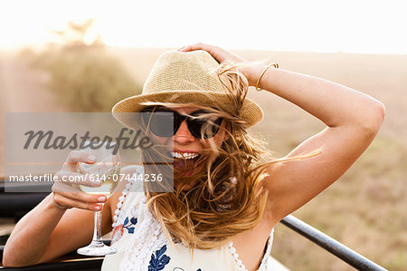 Young woman wearing hat holding glass of wine