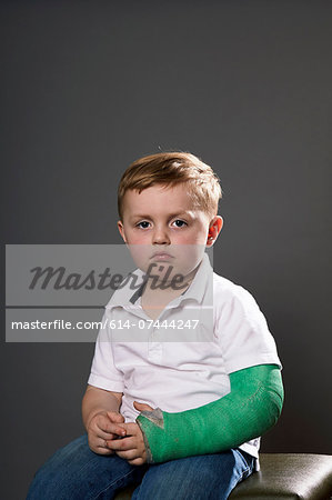 Portrait of sullen young boy with plaster cast on arm