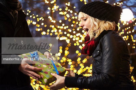 Young woman receiving xmas gift on city street