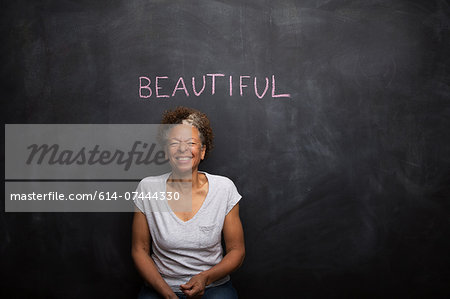 Senior woman in front of blackboard and the word beautiful