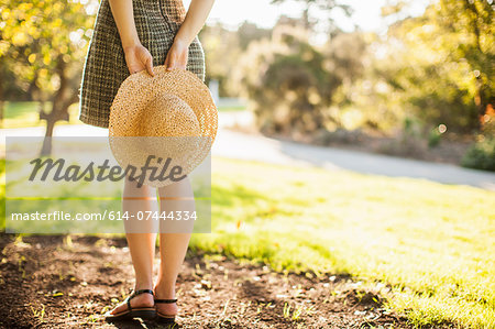 Cropped image of teenage girl holding sunhat behind her back