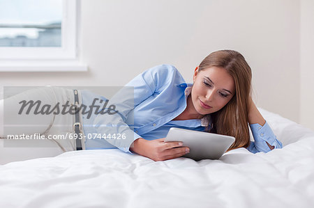 Beautiful woman using tablet computer on her bed