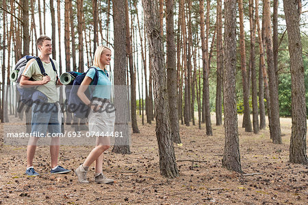 Full length of happy young couple hiking in forest