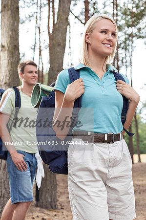 Happy young woman with man hiking in forest