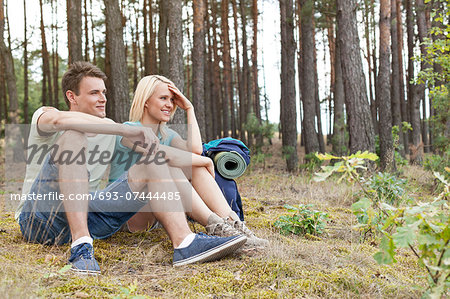 Full length of young hiking couple relaxing in woods