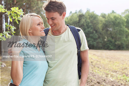 Romantic young couple looking at each other while hiking in forest