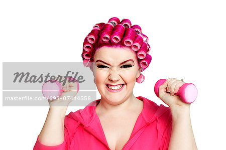 Portrait of a young woman happily lifting weights