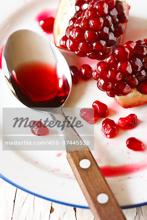Fresh ripe pomegranate and pomegranate juice on a spoon close-up.