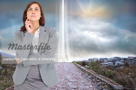 Focused businesswoman against rocky path leading to light beam