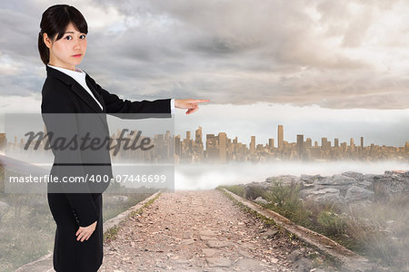 Focused businesswoman pointing against stony path leading to large urban sprawl