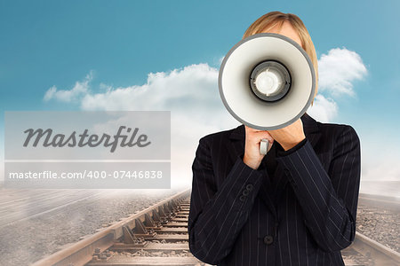 Closeup of a businesswoman with a megaphone hiding her face against train tracks leading over the horizon