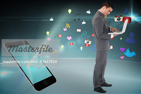 Standing businessman typing on his laptop against floating smartphone application icons