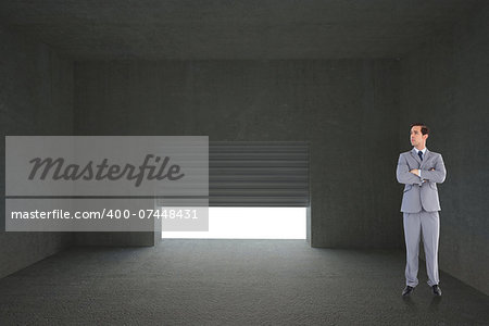 Serious businessman with arms crossed against shutter opening in dark room