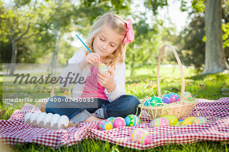 Cute Young Girl Happily Coloring Her Easter Eggs with Paint Brush in the Park.