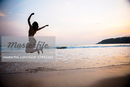 Tourist jumping on Mirissa Beach at sunset, South Coast of Sri Lanka, Southern Province, Sri Lanka, Asia