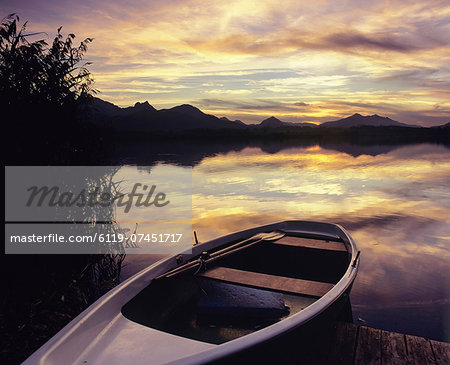 Rowing boat on Hopfensee Lake at sunset, near Fussen, Allgau, Bavaria, Germany, Europe Rowing boat on Hopfensee Lake at sunset, near Fussen, Allgau, Bavaria, Germany, Europe