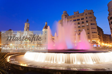 Illuminated fountain on Plaza del Ayuntamineto with town hall at dusk, Valencia, Comunidad Valencia, Spain, Europe