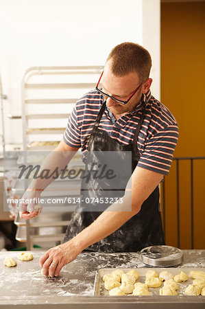 Male baker shaping dough in bakery