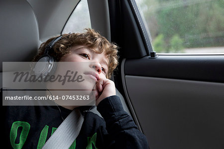 Boy in back seat of car, wearing headphones