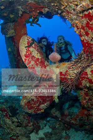 Divers near prop of sunken ship.