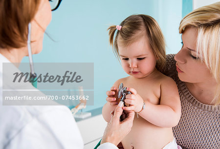 Doctor with Stethoscope in Exam Room with Baby Girl and Mother