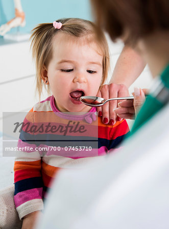 Doctor giving Baby Girl Spoonful of Medicine in Doctor's Office