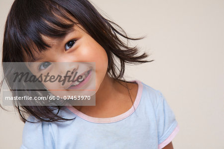 Close-up portrait of Asian toddler girl, looking at camera and smiling, studio shot on white background Close-up portrait of Asian toddler girl, looking at camera and smiling, studio shot on white background