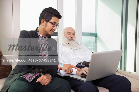 Grandfather and grandson using laptop in living room